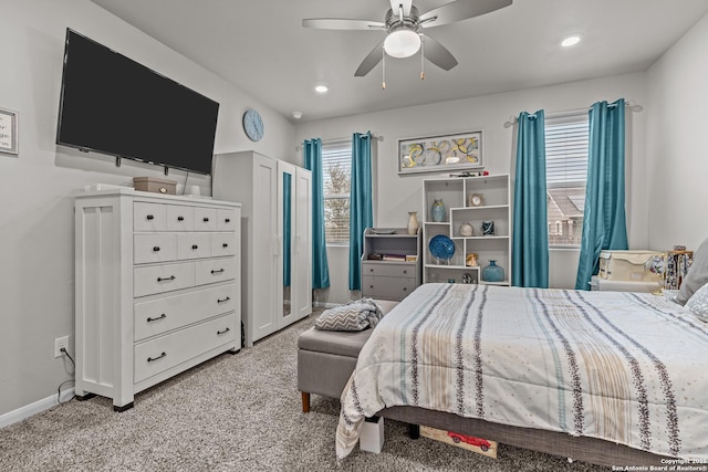 bedroom featuring light colored carpet, ceiling fan, baseboards, and multiple windows