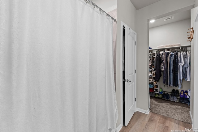 bathroom featuring visible vents, a spacious closet, and wood finished floors