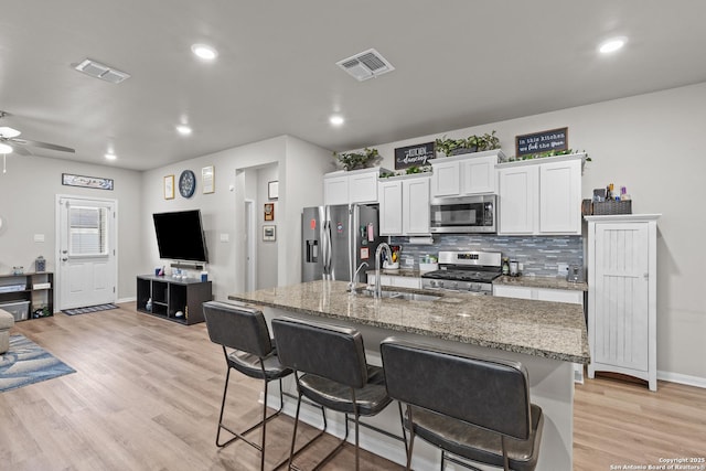 kitchen featuring appliances with stainless steel finishes, a sink, visible vents, and white cabinetry