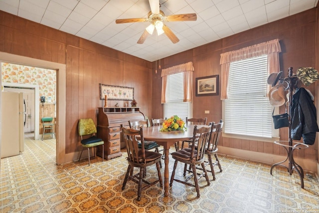 dining space featuring wood walls and a ceiling fan