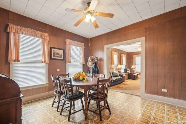 dining area with wooden walls, baseboards, and a ceiling fan