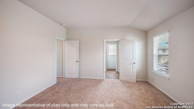 unfurnished bedroom featuring multiple windows, baseboards, vaulted ceiling, and light colored carpet