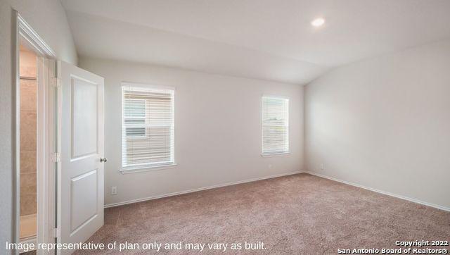 spare room featuring lofted ceiling, baseboards, and light colored carpet