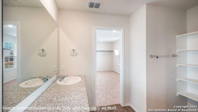 bathroom featuring a spacious closet, visible vents, and vanity