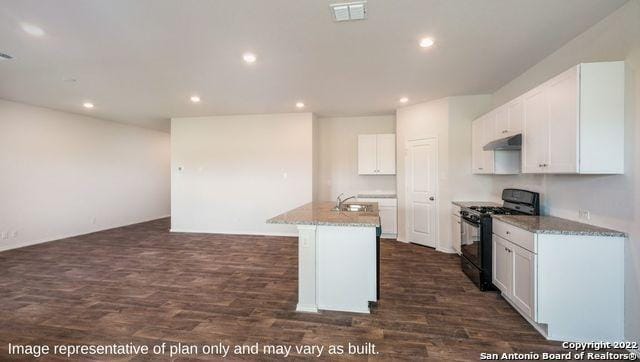 kitchen featuring a center island with sink, visible vents, under cabinet range hood, white cabinetry, and gas stove