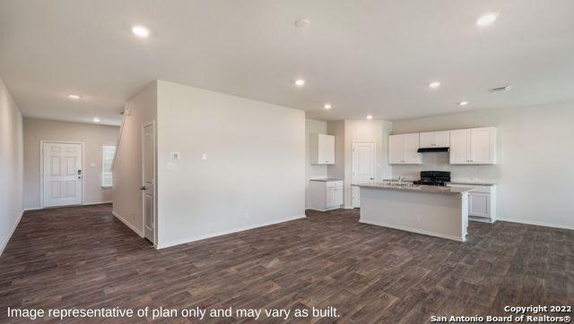 kitchen featuring dark wood finished floors, stove, a kitchen island with sink, light countertops, and white cabinetry