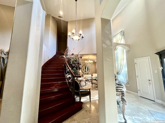 stairs featuring an inviting chandelier, visible vents, a high ceiling, and baseboards