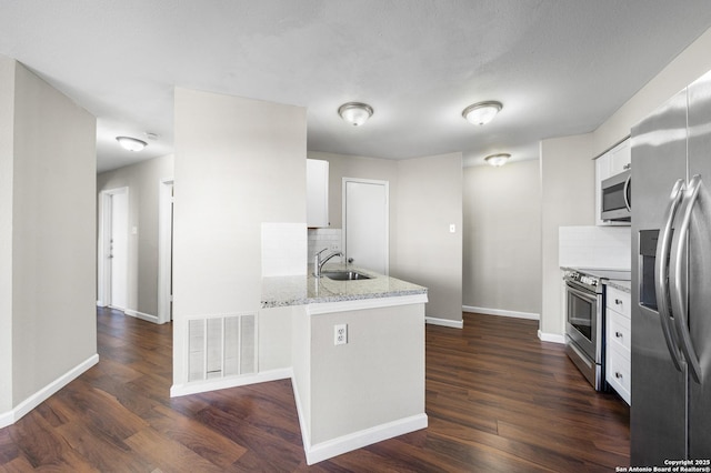 kitchen with light stone counters, visible vents, appliances with stainless steel finishes, white cabinetry, and a sink