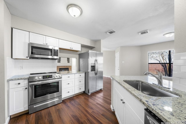 kitchen featuring stainless steel appliances, a sink, visible vents, white cabinetry, and light stone countertops