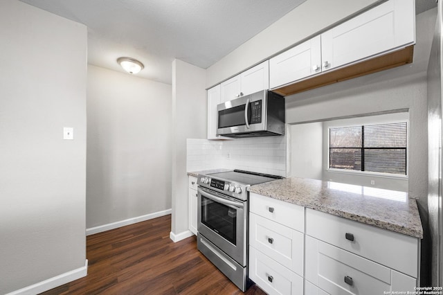 kitchen with tasteful backsplash, baseboards, white cabinets, appliances with stainless steel finishes, and light stone countertops