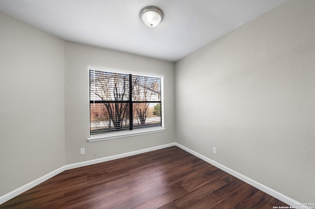 spare room with dark wood-style flooring and baseboards