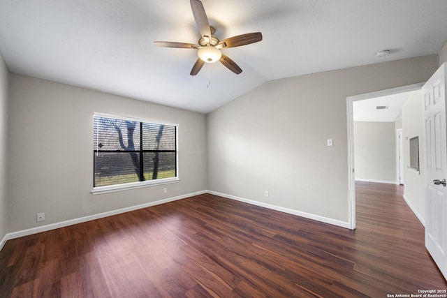 empty room featuring visible vents, baseboards, ceiling fan, dark wood-type flooring, and vaulted ceiling