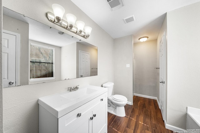 bathroom featuring visible vents, vanity, toilet, and wood finished floors