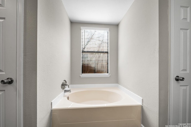 bathroom featuring a textured wall and a garden tub