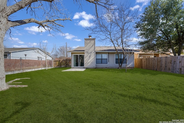 rear view of house with a patio area, a fenced backyard, a lawn, and a chimney