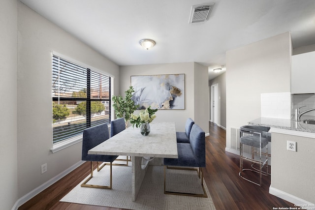 dining space with dark wood-type flooring, visible vents, and baseboards