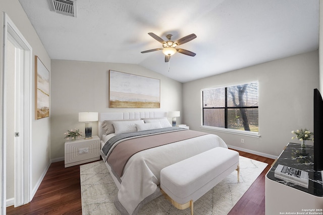 bedroom with dark wood-style floors, visible vents, vaulted ceiling, and baseboards