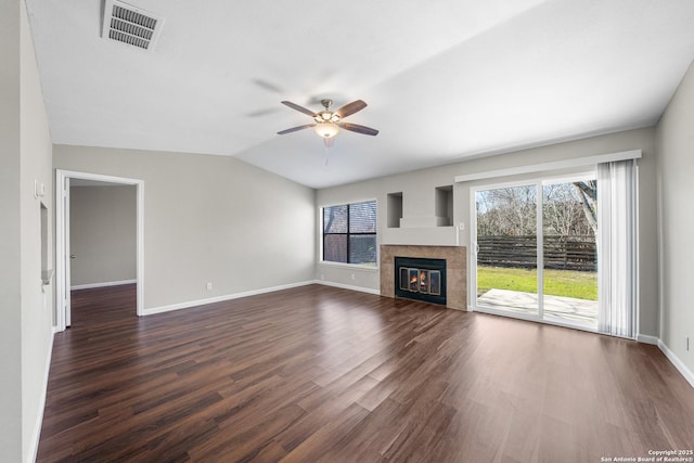 unfurnished living room with visible vents, dark wood-type flooring, vaulted ceiling, a tile fireplace, and baseboards