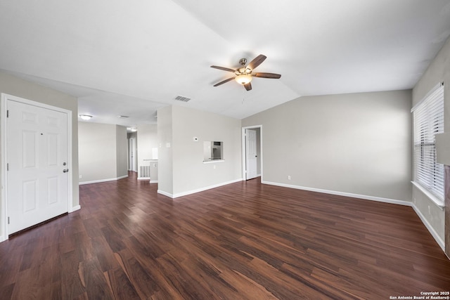 spare room with baseboards, visible vents, ceiling fan, dark wood-type flooring, and vaulted ceiling