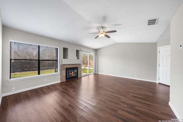 unfurnished living room with a glass covered fireplace, dark wood finished floors, visible vents, and vaulted ceiling