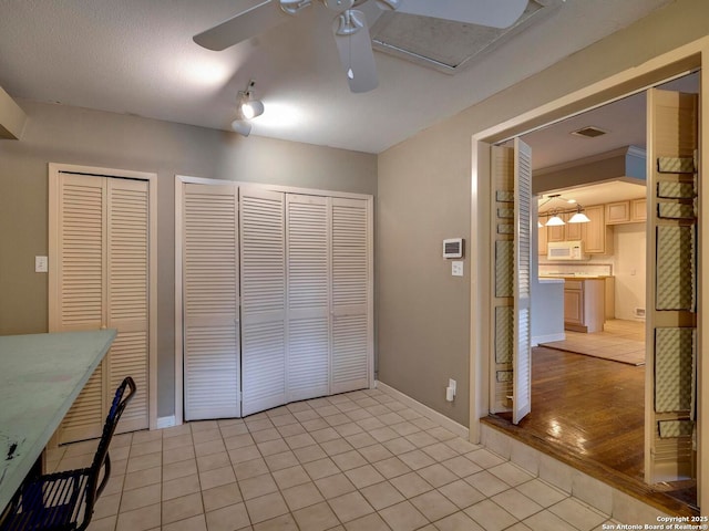 interior space with light tile patterned floors, baseboards, visible vents, and a ceiling fan