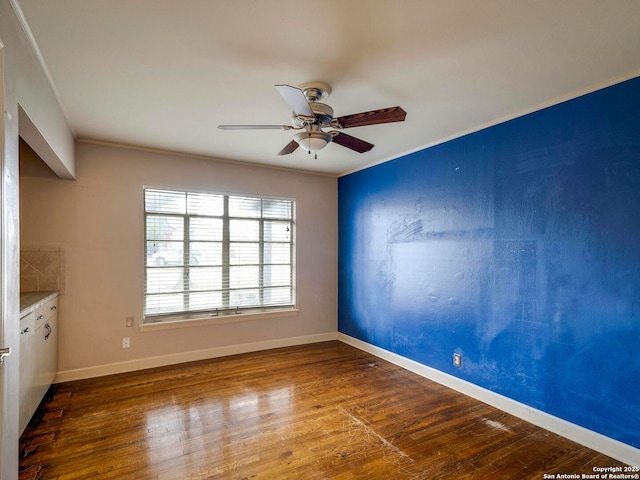 unfurnished room featuring a ceiling fan, baseboards, wood finished floors, and ornamental molding