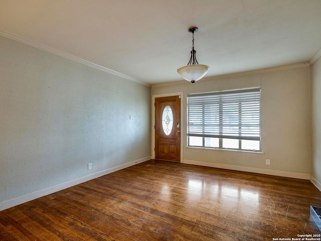 foyer featuring dark wood-type flooring, ornamental molding, and baseboards