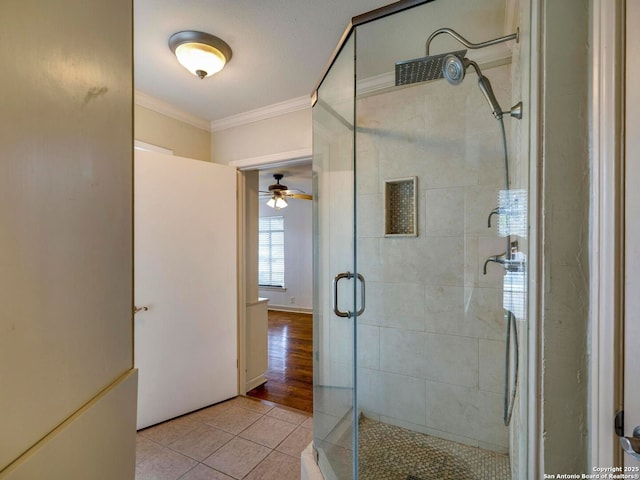 full bathroom featuring a stall shower, ceiling fan, crown molding, and tile patterned floors