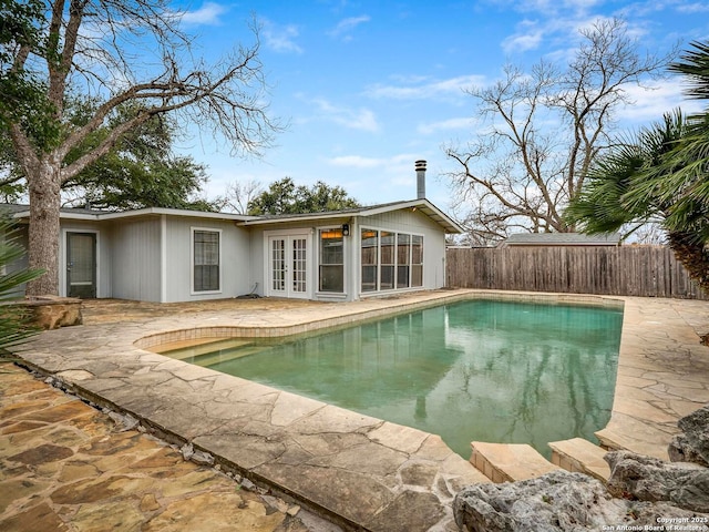 view of swimming pool featuring a patio, french doors, fence, and a fenced in pool