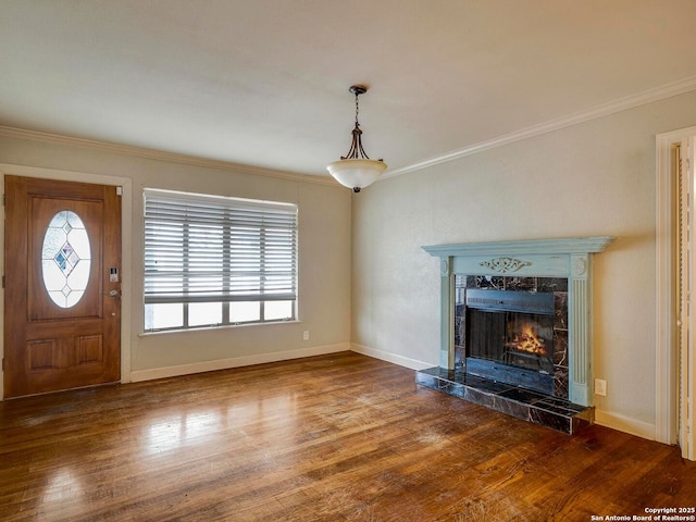 unfurnished living room with ornamental molding, a tile fireplace, baseboards, and wood finished floors