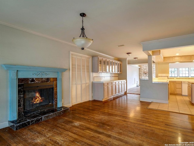 unfurnished living room with baseboards, ornamental molding, a high end fireplace, and light wood-style floors