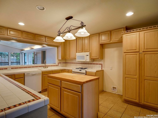 kitchen with white appliances, tile countertops, a center island, light brown cabinets, and pendant lighting