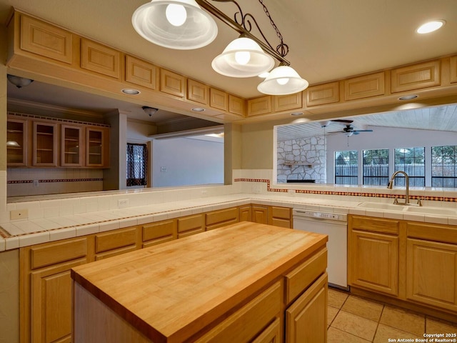 kitchen featuring dishwasher, butcher block counters, a sink, and a center island