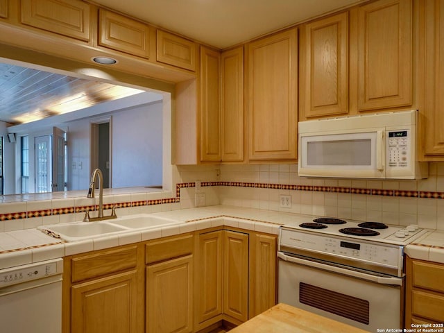 kitchen featuring tile countertops, white appliances, a sink, and decorative backsplash