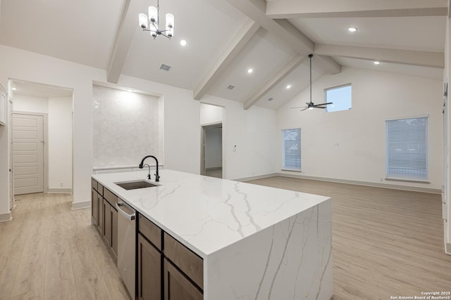 kitchen with light stone counters, a sink, open floor plan, hanging light fixtures, and stainless steel dishwasher