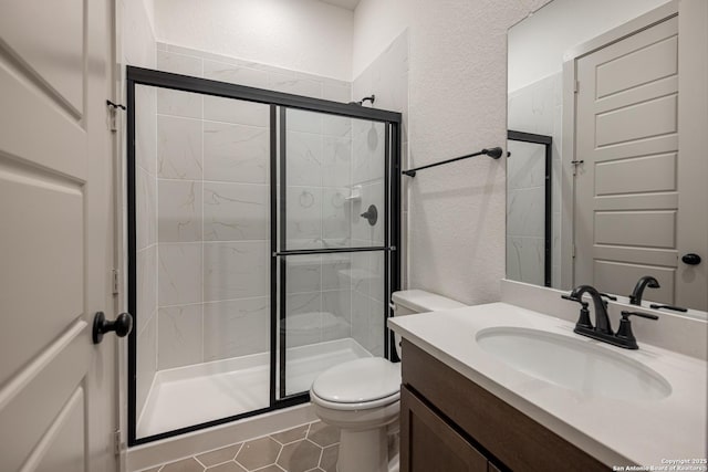 bathroom with a stall shower, a textured wall, vanity, and toilet