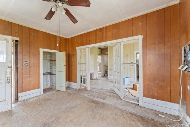 spare room featuring a ceiling fan and wooden walls