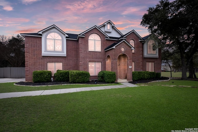 view of front of house featuring brick siding, a front yard, and fence