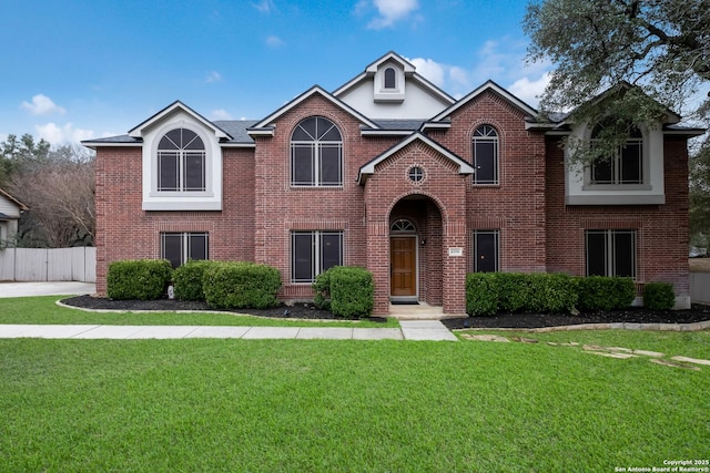 traditional home with a front yard, brick siding, and fence