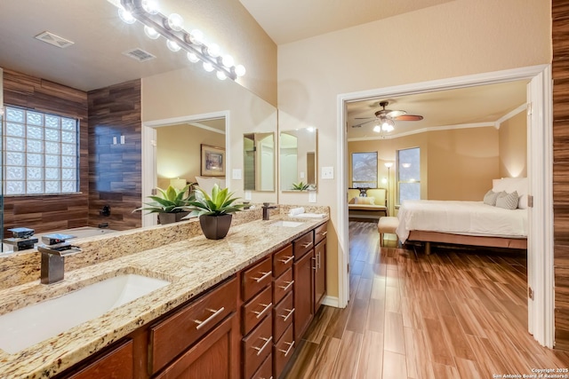 ensuite bathroom with visible vents, a sink, ensuite bath, and wood finished floors