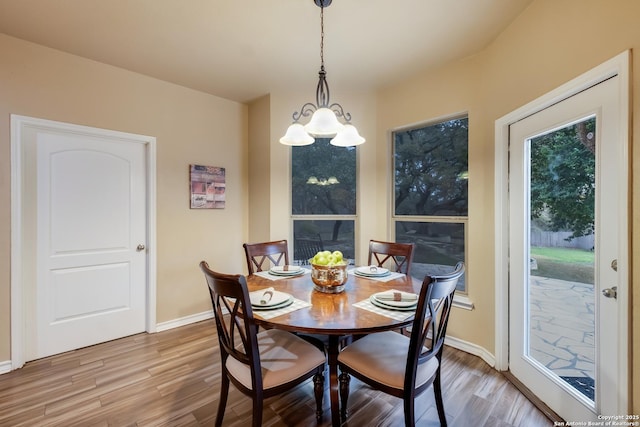 dining area featuring a notable chandelier, baseboards, and wood finished floors