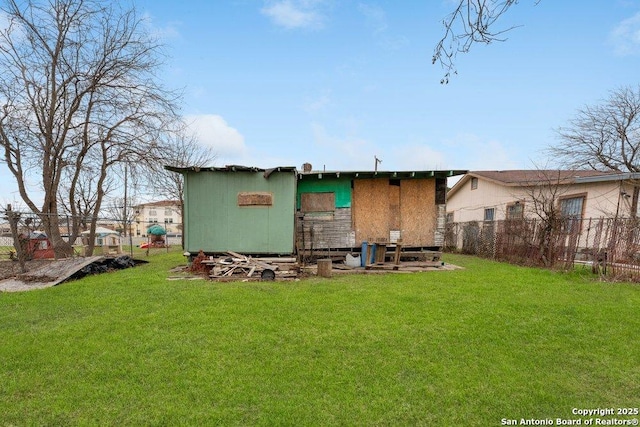 rear view of property featuring fence and a yard