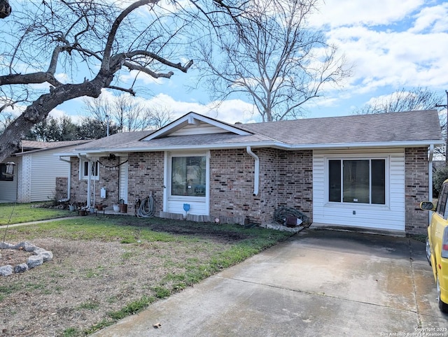 ranch-style home with a front yard, brick siding, and roof with shingles