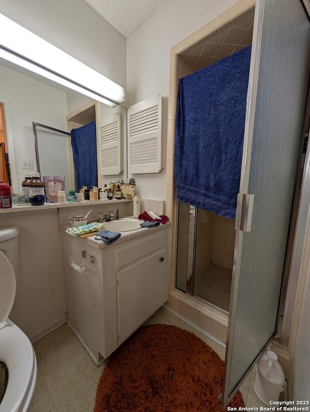 bathroom featuring a textured ceiling, toilet, a shower stall, and vanity