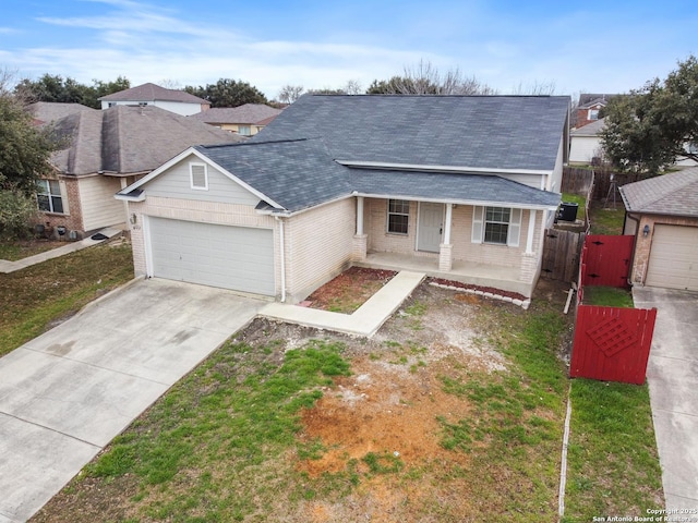 ranch-style house featuring a porch, concrete driveway, a front yard, fence, and a garage