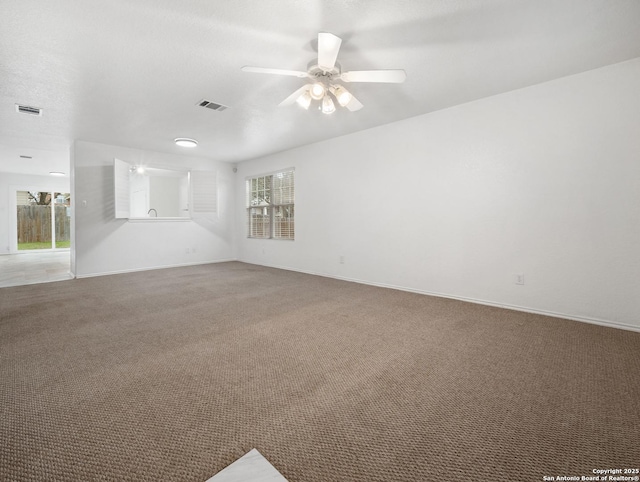 carpeted empty room with ceiling fan, visible vents, and baseboards