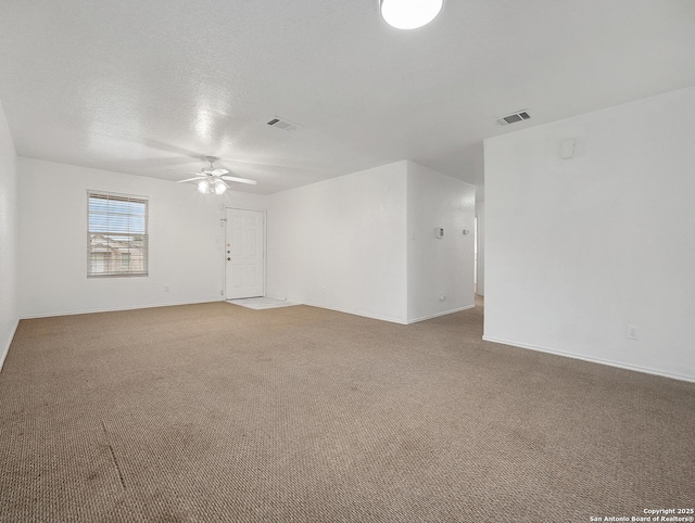 carpeted empty room featuring a ceiling fan, visible vents, a textured ceiling, and baseboards