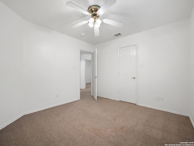 unfurnished bedroom featuring a textured ceiling, carpet floors, visible vents, and a ceiling fan