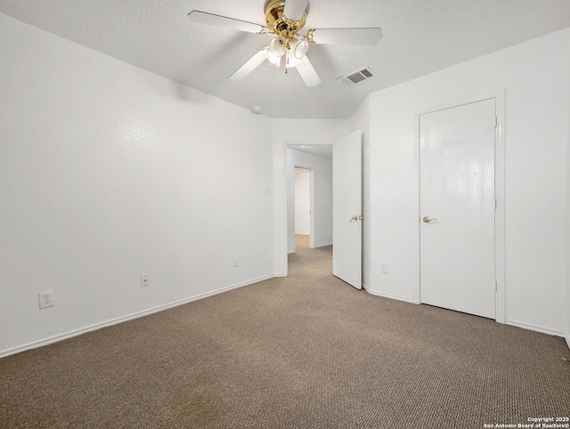 unfurnished bedroom featuring a textured ceiling, carpet flooring, visible vents, baseboards, and a ceiling fan