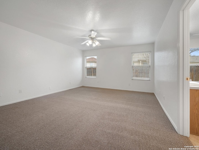 empty room featuring a ceiling fan, light carpet, a textured ceiling, and baseboards